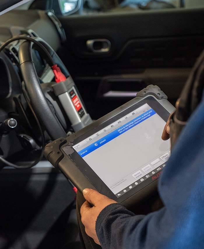 Technicien utilisant une valise de diagnostic électronique à l’intérieur d’une voiture.