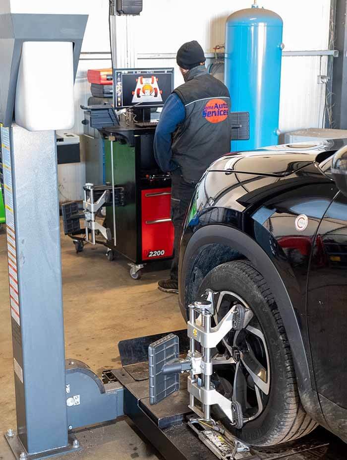 Technicien effectuant un contrôle de parallélisme sur une voiture avec banc de géométrie